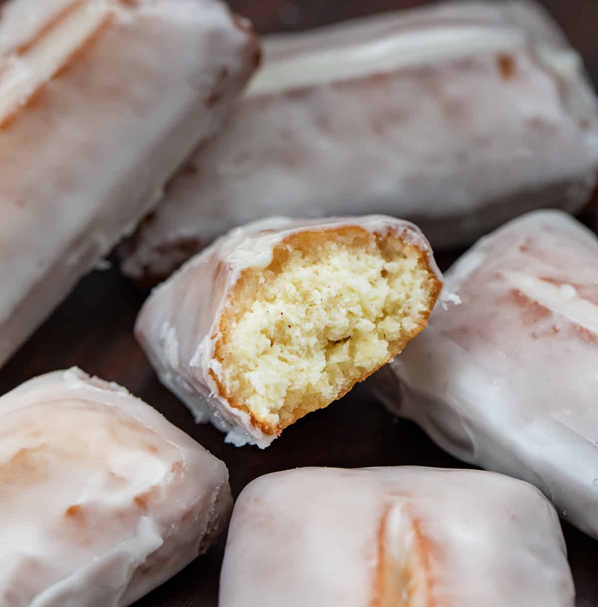 Donut sticks, also known as donut fries, are rectangles of fried dough and are the perfect snack for any donut lover. Dip them in a glossy glaze for a classic treat, or get creative and roll them in cinnamon and sugar, dust them with confectioners' sugar, or even add your favorite sprinkles or chopped nuts. I will also let you know how you can make these in the oven and an air fryer. Donut Sticks on a Butcher Block with One Torn in Half Showing Inside.