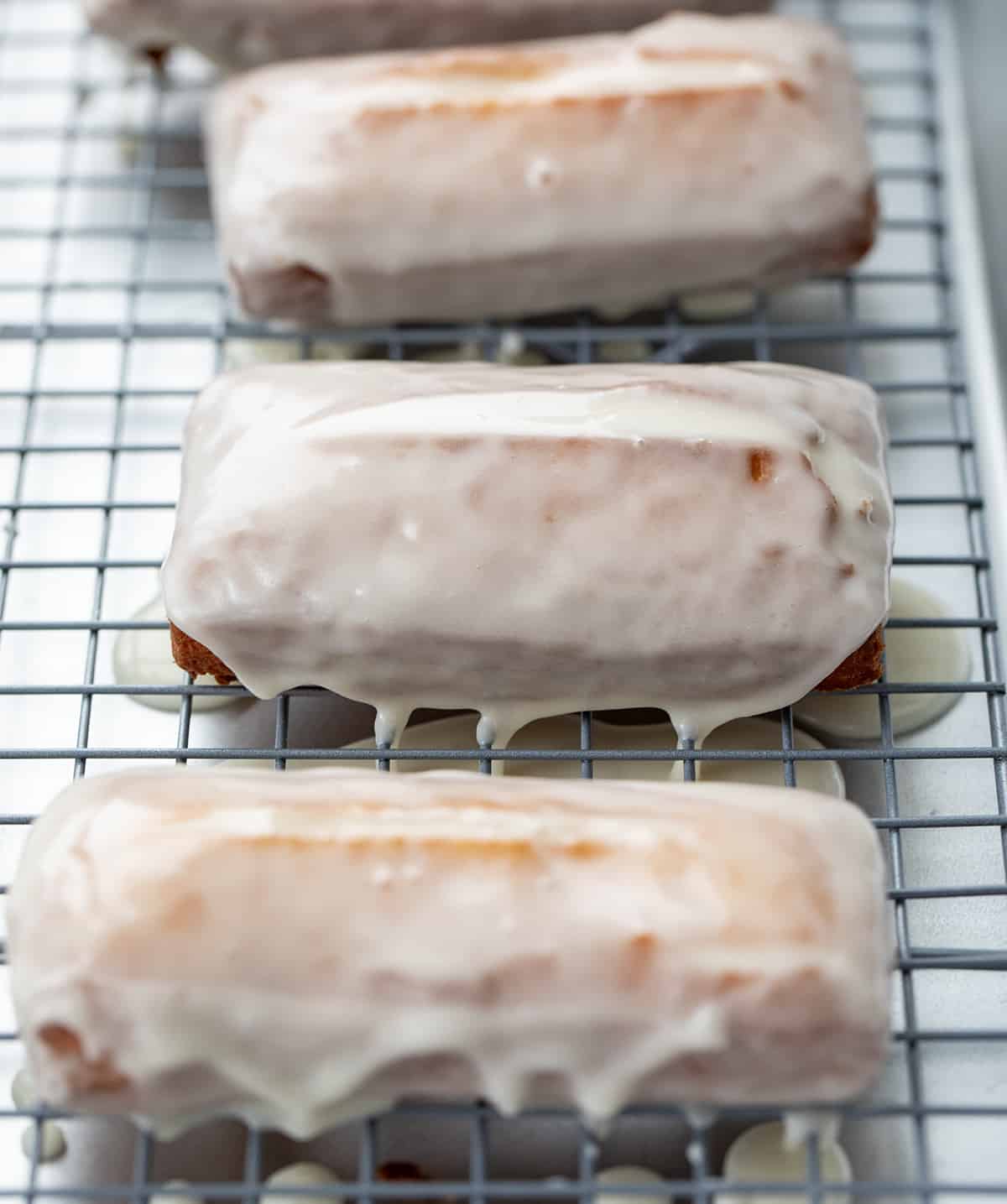 Donut sticks, also known as donut fries, are rectangles of fried dough and are the perfect snack for any donut lover. Dip them in a glossy glaze for a classic treat, or get creative and roll them in cinnamon and sugar, dust them with confectioners' sugar, or even add your favorite sprinkles or chopped nuts. I will also let you know how you can make these in the oven and an air fryer. Donut Sticks on a rack after glaze has been applied.